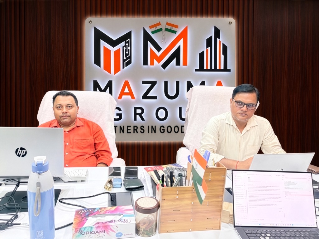 Mazuma India founders and directors sitting at their office desk under the Mazuma Group company board